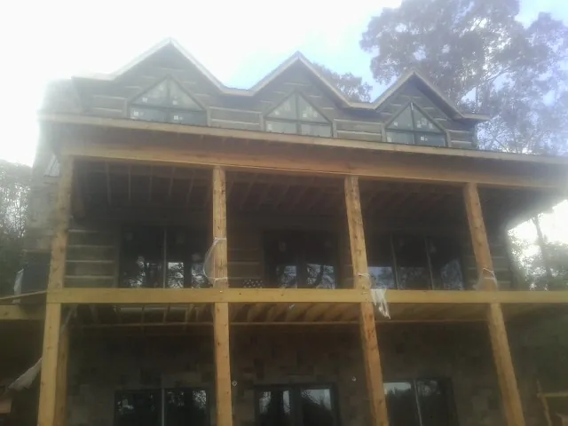 Dormers and porch framing on a large log home under construction — Roof Coating work by our crew in Wakonda