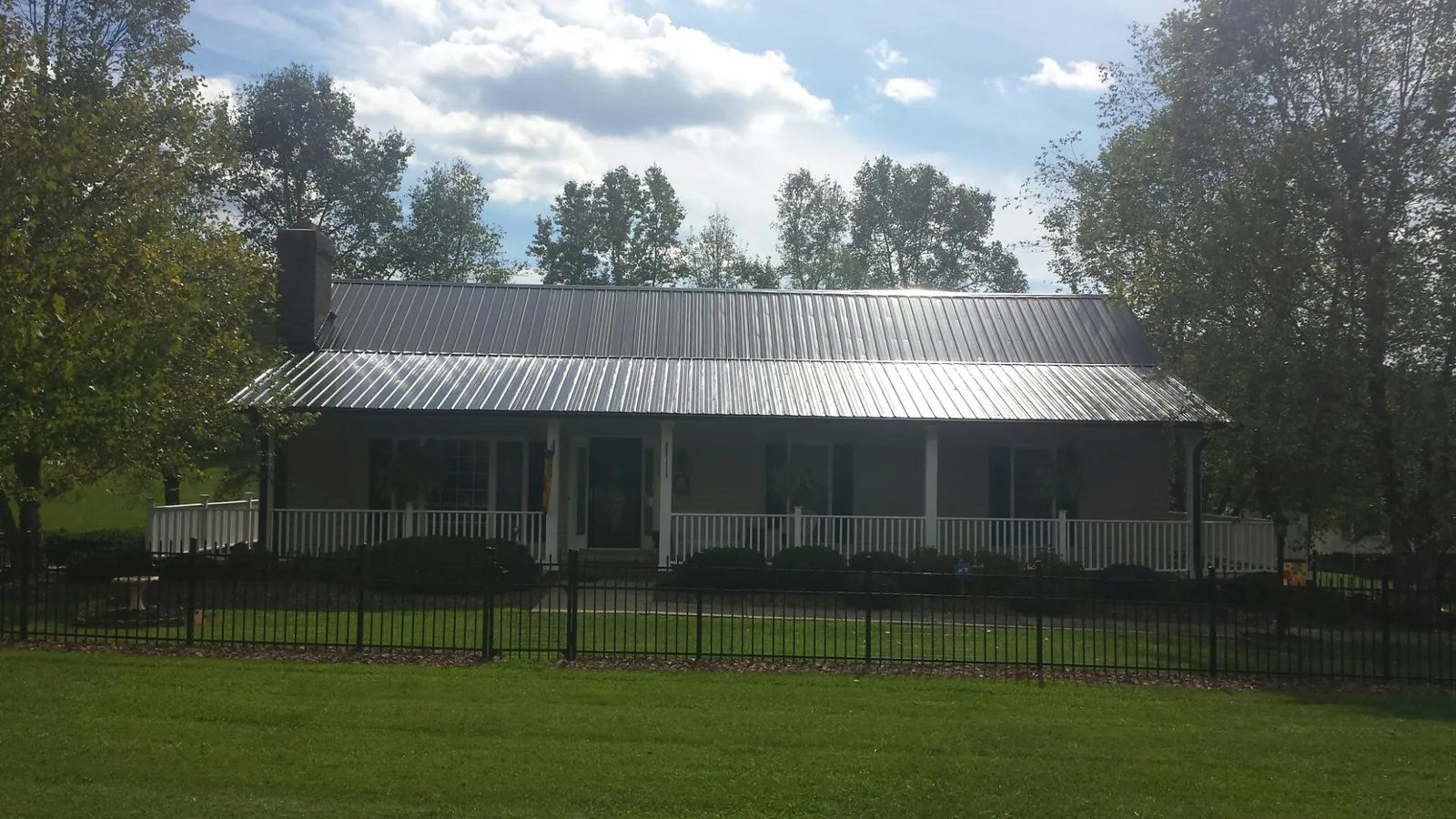 Gray metal roof on a brick ranch with a full width front porch — Gutter Guard Installation work by our crew in Wakonda
