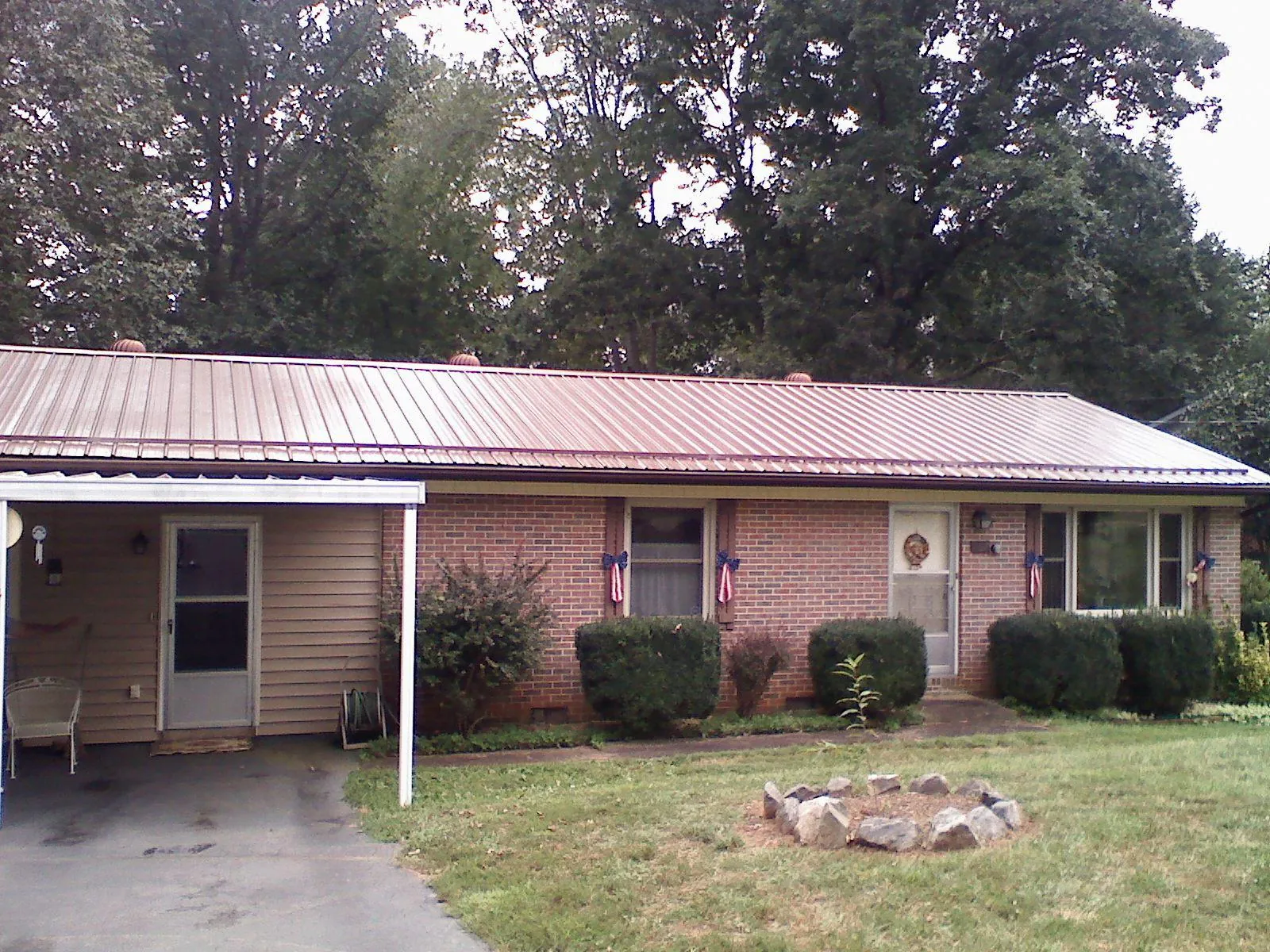 Bronze metal roof and carport on a brick ranch home — Roof Repair work by our crew in Wakonda