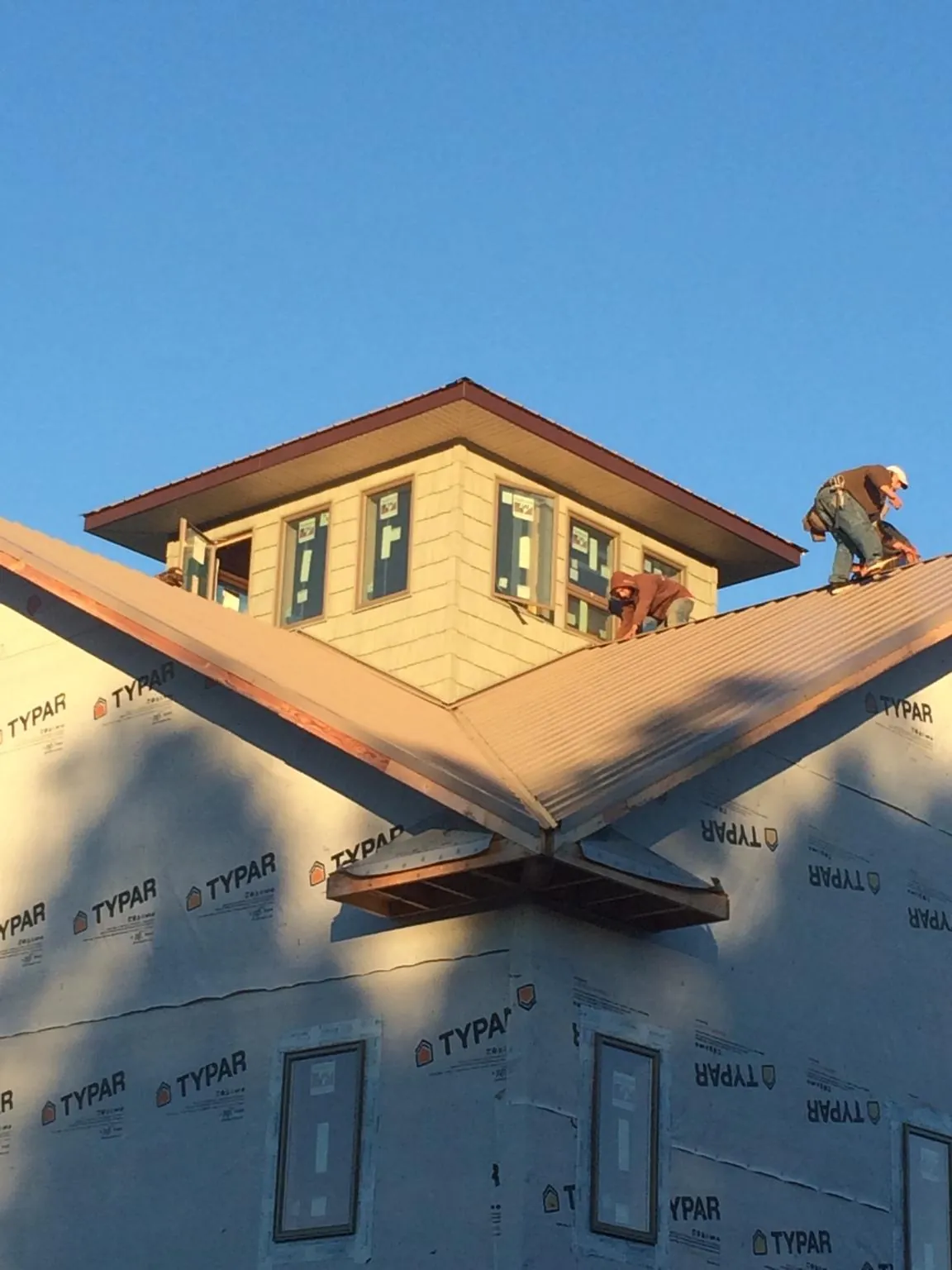 Roofers working around a rooftop cupola on a new metal roof at sunset — Roof Waterproofing in Wakonda by Roofing Brothers